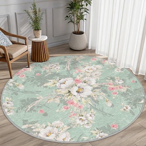 May include: A round, green and white floral area rug with a vintage floral pattern. The rug has a light green background with white and pink flowers.