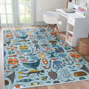 Puede incluir: Una alfombra azul y blanca con temática náutica. La alfombra presenta una variedad de criaturas marinas, incluyendo peces, ballenas y pulpos. También hay anclas, salvavidas y otros símbolos náuticos. La alfombra es perfecta para una habitación infantil o un hogar con temática de playa.