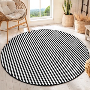 May include: Black and white striped round rug with a black border. The rug is on a light wood floor.