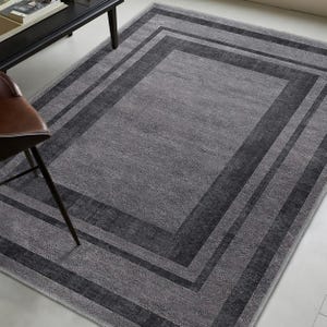 May include: A gray area rug with a dark gray border. The border has multiple stripes.