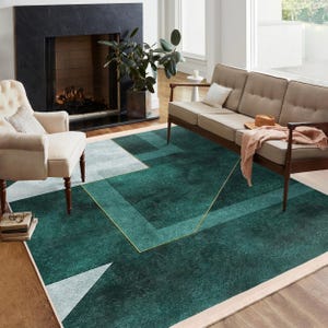 Peut inclure: Un tapis de salon géométrique vert et blanc avec des accents dorés. Le tapis est dans un salon avec un canapé et une cheminée.