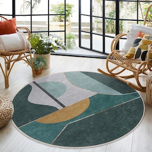 May include: A round, green, gold, and white area rug with an abstract geometric design. The rug is on a light wood floor.