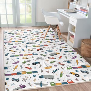 May include: A white and gray area rug with a colorful pattern of cars, boats, trains, and airplanes. The rug has a white background with gray accents and features a variety of colorful vehicles.