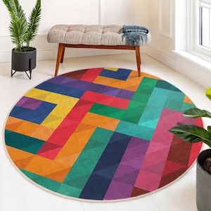 May include: A round area rug with a geometric pattern in shades of red, orange, yellow, green, blue, purple, and brown. The rug has a white border.
