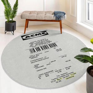 Puede incluir: Una alfombra redonda blanca con un recibo en blanco y negro impreso en ella. El recibo es para una alfombra de ACME ALHUMT. El recibo muestra el número de artículo, el subtotal, el total, el efectivo, el código postal, el cambio debido y la fecha. El recibo también muestra los artículos comprados, la tasa de IVA y el importe del impuesto.