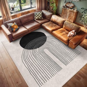 May include: A white and black geometric rug with a large black circle and a series of vertical lines forming an arch shape.