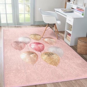 May include: Pink area rug with a design of gold, pink, and white balloons with glitter accents.