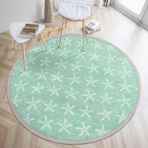May include: A round, light green rug with a white starfish pattern. The rug has a fringe border.