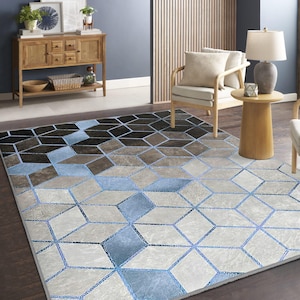 Può includere: Un tappeto con motivo geometrico in tonalità blu chiaro, grigio e marrone. Il tappeto ha un design moderno con un motivo ripetitivo di quadrati e rombi.