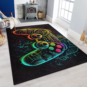 Puede incluir: Una alfombra negra y arcoíris con un gran gráfico de un mando de videojuego. El mando está delineado en colores arcoíris y tiene un fondo negro.