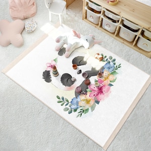 Puede incluir: Un oso panda blanco y negro con una corona de flores alrededor de su cabeza. El panda está rodeado de flores rosas, azules y amarillas. El fondo es blanco.