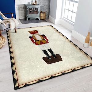 Puede incluir: Una alfombra blanca y crema con un borde negro presenta una ilustración de estilo vintage de un soldado de juguete rojo y dorado de pie sobre una caja de madera. El soldado sostiene un rifle y lleva un sombrero y botas negras.