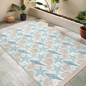 Puede incluir: Una alfombra blanca con un patrón repetitivo de conchas y estrellas de mar en tonos azules y marrones. La alfombra tiene un borde beige.