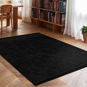 May include: A black area rug with a subtle textured pattern. The rug has a simple, modern design and is perfect for adding a touch of sophistication to any room.