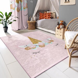 Può includere: Un tappeto a forma di unicorno rosa e oro con un corno glitterato e accenti floreali. Il tappeto è perfetto per la camera da letto di un bambino o una sala giochi.