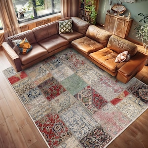 Pode incluir: Um tapete de patchwork multicolorido com um visual desgastado e vintage. O tapete é composto por vários quadrados e retângulos de diferentes cores e padrões, incluindo vermelho, azul, verde e bege. O tapete está colocado sobre um piso de madeira em uma sala de estar, com um sofá de couro marrom no fundo.