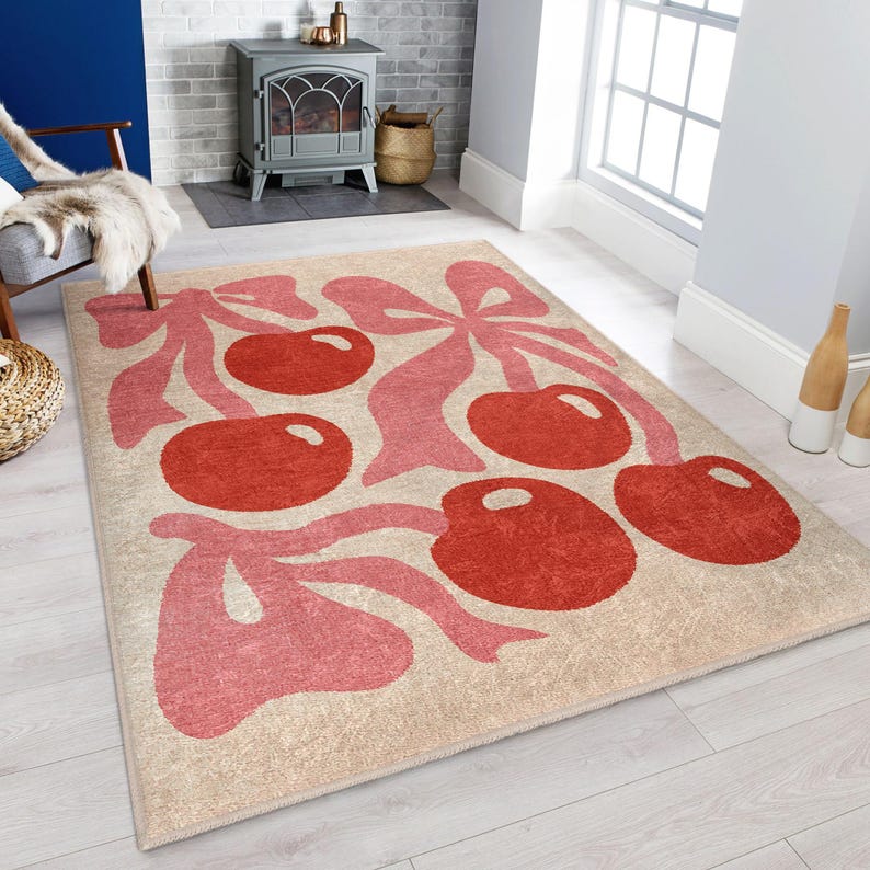 May include: A beige rug with a pink and red cherry design. The cherries are stylised and have a retro feel. The rug is perfect for adding a touch of whimsy to any room.