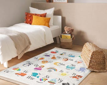 May include: A white alphabet rug with colorful illustrations of animals, objects, and letters. The rug features the letters A through Z with corresponding images. The rug is on a light wood floor.