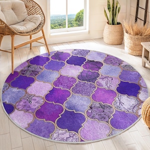Puede incluir: Una alfombra redonda de color morado y dorado con un patrón geométrico. La alfombra tiene un diseño de inspiración marroquí con detalles intrincados.