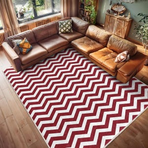 Puede incluir: Una alfombra de área con patrón de chevron rojo y blanco con un sofá seccional de cuero marrón en el fondo.
