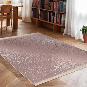 Pode incluir: Um tapete de área rosa e branco com um padrão sutilmente salpicado. O tapete tem um efeito degradê, passando de um rosa mais escuro para um rosa mais claro.