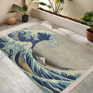 May include: A rug featuring a vintage-style illustration of a large wave with three boats in the foreground. The wave is blue and white, and the boats are brown and white. The background is a light beige colour.