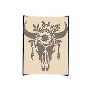 May include: A brown and white bull skull with a floral design and feathers. The skull is surrounded by a wreath of flowers and leaves.