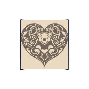 May include: A decorative heart-shaped design featuring a bear illustration within an ornate, swirling pattern. The bear is smiling, and the design is in shades of brown and beige, with a dark blue border.