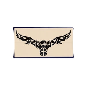 May include: Black and white silhouette of an owl with spread wings. The owl has a tribal design and is facing forward.