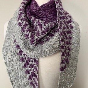 May include: A gray and purple knitted scarf with a geometric pattern. The scarf is draped over a white mannequin.