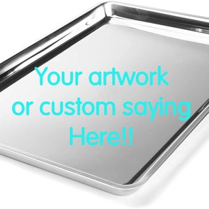 May include: A rectangular silver-colored metal baking tray with a raised rim. The center of the tray features the cyan text "Your artwork or custom saying Here!!". A circular logo in the top left corner contains the text "julie's homemade gems".