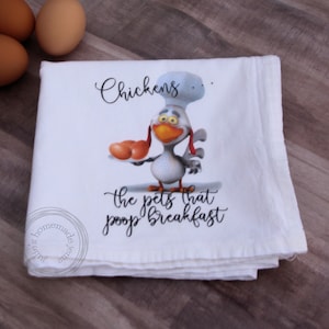May include: White kitchen towel with a cartoon chicken wearing a chef's hat and holding a plate of eggs. The text on the towel reads "Chickens: the pets that poop breakfast."