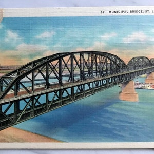 May include: A vintage postcard featuring a black and white photo of a large steel bridge over a river. The postcard is titled "67 MUNICIPAL BRIDGE, ST. LOUIS, MO."