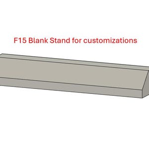 May include: A rectangular, light gray stand with a slanted front edge. The text "F15 Blank Stand for customizations" is in red above the stand. The stand is designed for custom projects.