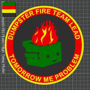 May include: A circular patch with the text "DUMPSTER FIRE TEAM LEAD TOMORROW ME PROBLEM". The design features a green dumpster with flames and a flag in the upper left corner. The text is in yellow and red.
