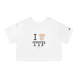 May include: White crop top with the text "I 🐶 TTP" in black. A cartoon dog graphic is above the letters TTP. The Champion logo is on the sleeve.