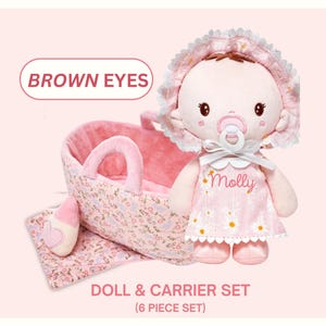 May include: A plush doll and carrier set. The doll has brown eyes, a pacifier, and wears a pink dress with the name "Molly". The carrier and blanket feature a floral pattern. The set includes a doll, carrier, blanket, and other accessories.