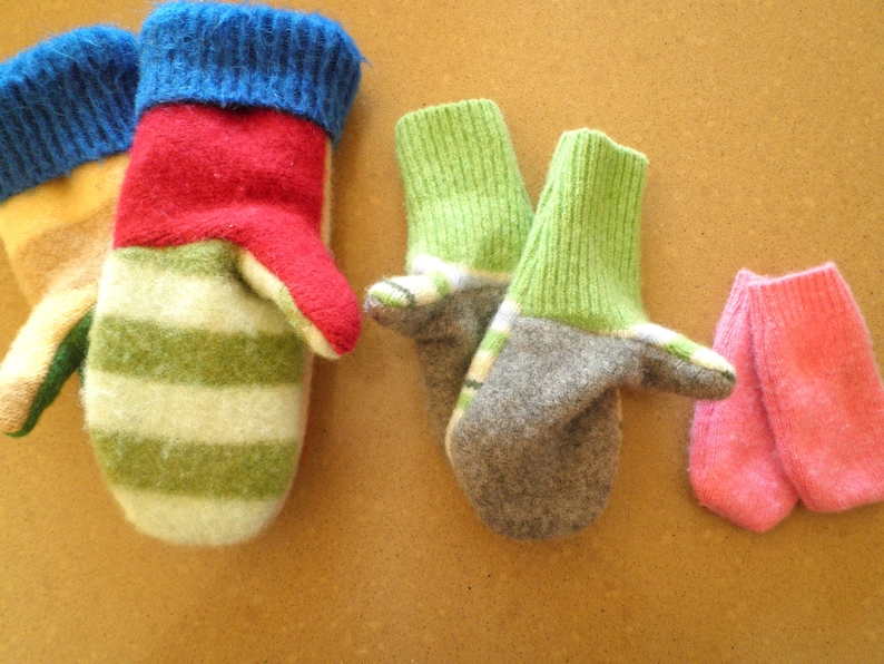 May include: Four pairs of knitted mittens in various colors and patterns. The mittens are made of wool and have a soft, cozy texture. The colors include green, red, blue, gray, and pink.