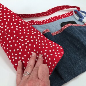May include: A red and white polka dot fabric apron with a denim pocket and a red and white trim. The apron has a blue and white patterned fabric lining and a denim strap.