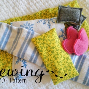 May include: A sewing pattern for a set of four heat packs. The heat packs are made of fabric with different patterns, including yellow flowers, blue stripes, and snowflakes. The text "sewing - PDF Pattern" is visible in the image.