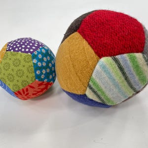 Puede incluir: Dos bolas de patchwork coloridas. Una bola está hecha de recortes de tela en varios colores y patrones. La otra bola está hecha de recortes de tela de punto en tonos de rojo, amarillo, azul y verde.