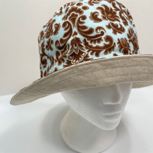 May include: A brown and blue patterned bucket hat with a beige brim.