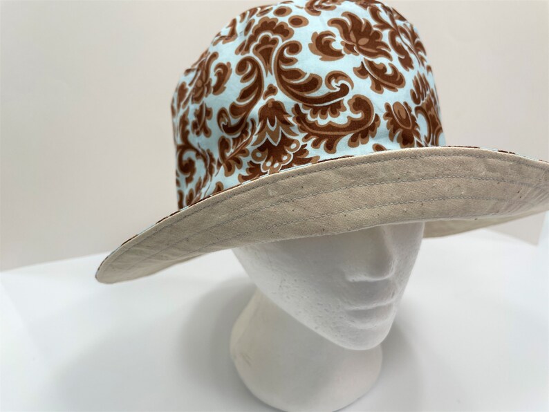 May include: A brown and blue patterned bucket hat with a beige brim.