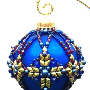 May include: A blue glass Christmas bauble with gold, red and blue beaded embellishments. The bauble has a gold wire hanger.