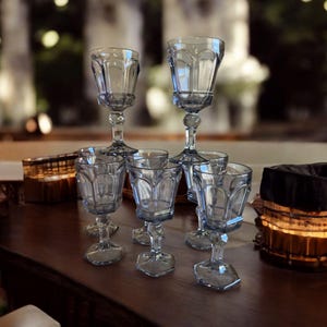 May include: A set of six blue glass goblets with a fluted design. The goblets are arranged in a semi-circle on a wooden surface.