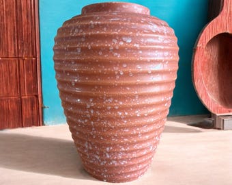 May include: A brown ceramic vase with a textured, ribbed surface and white speckles. The vase has a rounded, bulbous shape.