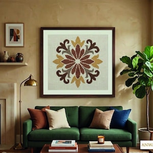 May include: A framed floral tapestry with a brown wooden frame hangs above a green sofa. The tapestry features a symmetrical design in shades of brown, yellow, and cream. Decorative pillows in various colors and textures adorn the sofa. A floor lamp and a potted plant are also visible.