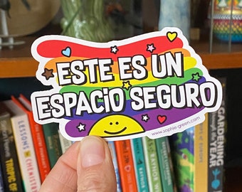 May include: A rainbow-colored sticker with the text "ESTE ES UN ESPACIO SEGURO" in white lettering. The sticker also features a yellow smiley face and stars. The website address "www.sophie-green.com" is printed at the bottom of the sticker.
