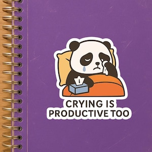Pode incluir: Um adesivo com um panda de desenho animado na cama com um lenço e uma caixa de lenços. O texto diz "Chorar também é produtivo."