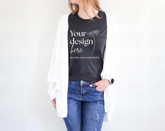 May include: A black t-shirt with the text "Your design here" and a floral design, worn with blue jeans and a white cardigan. The text "Real shirt. Real model. Real fit." is also visible.